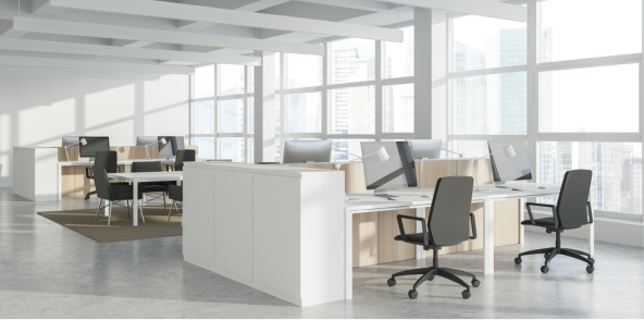 An office space featuring desks and chairs arranged in front of a large window, allowing natural light to illuminate the area.